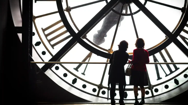 Wie wirkt sich die Zeitumstellung auf hochsensible Menschen aus? Zwei Kinder hinter einer Turmuhr