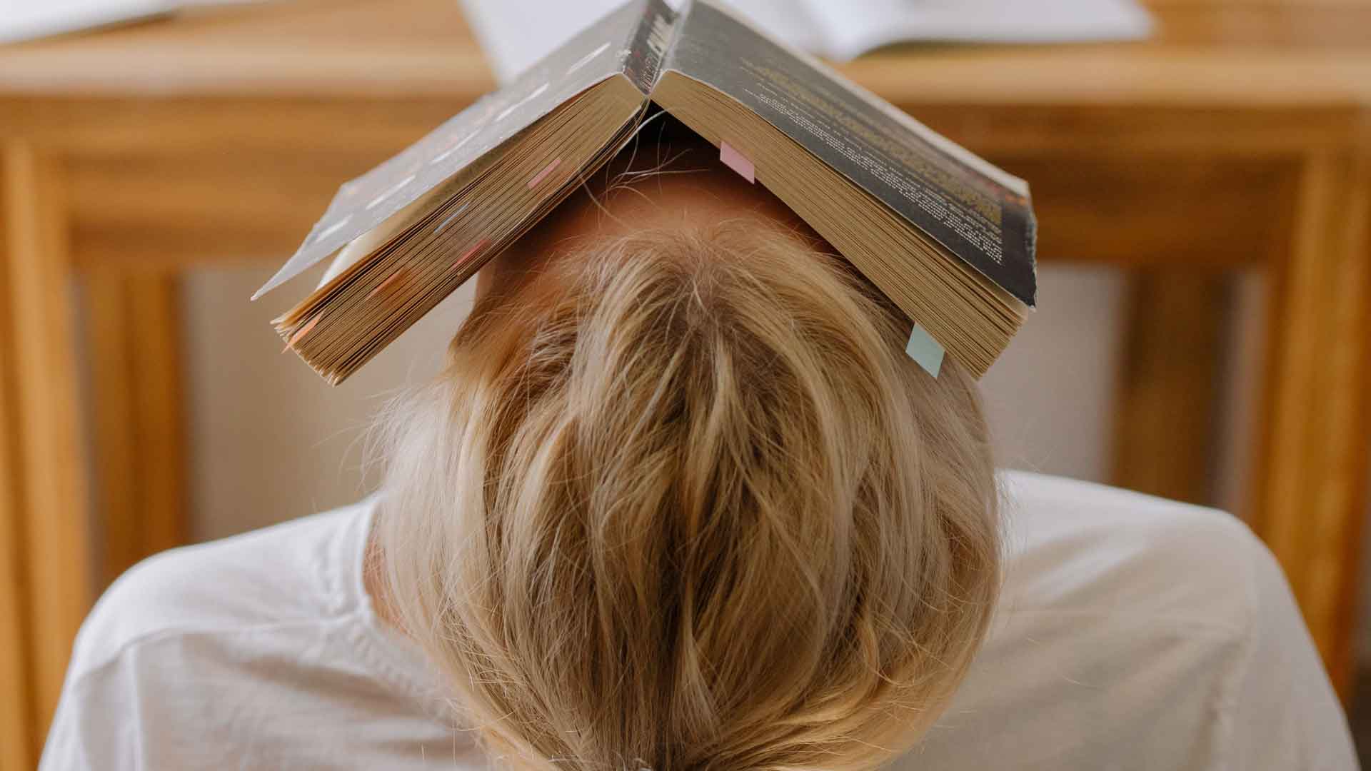Wie können Hochsensible mit Weltschmerz besser umgehen? Aufgeklapptes Buch auf der Stirn